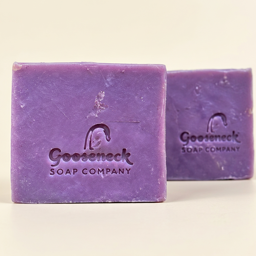 Two purple Lavender Rose soap bars stamped with Gooseneck Soap Company branding on a warm ivory background